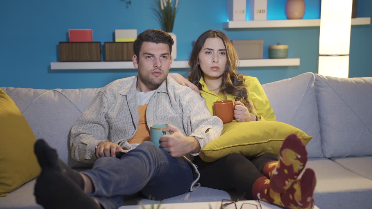 пара, смотрящая телевизор дома, удивлена новостями, которые они видят, они паникуют.