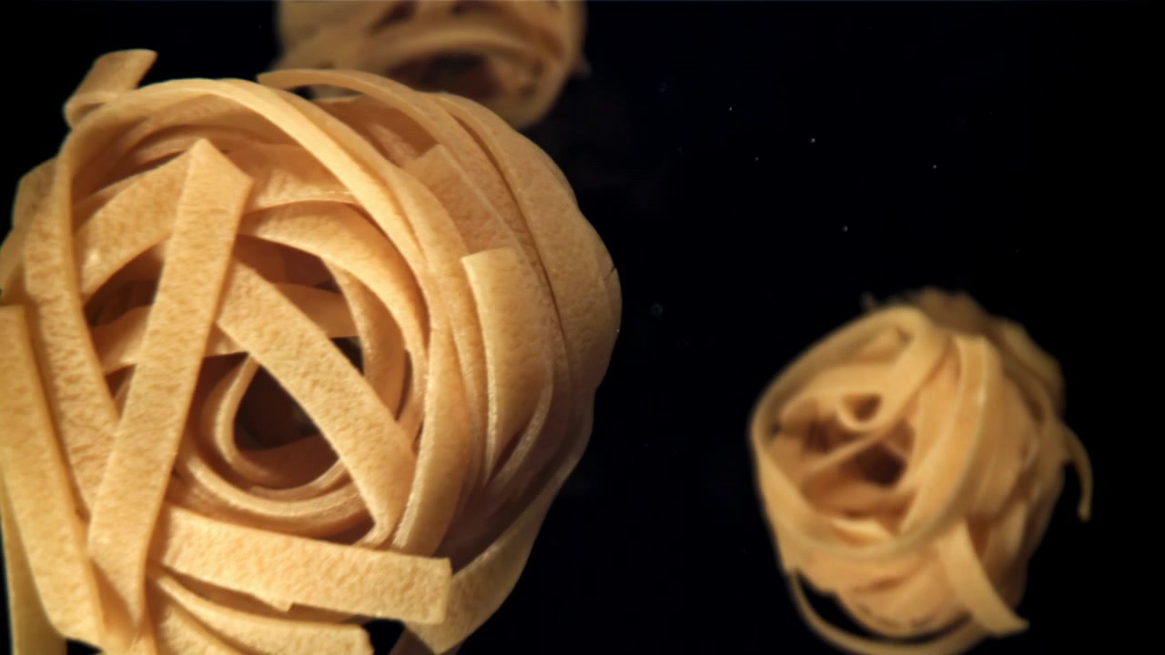 Tagliatelle che cadono al rallentatore su sfondo nero