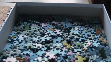 View-over-a-box-of-jigsaw-puzzle-pieces-slow-motion-50i