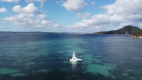 drone volando sobre un pequeño barco de pesca cerca de la costa del océano pacífico
