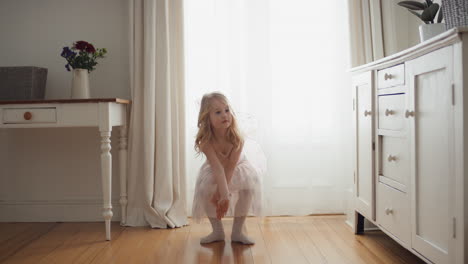 mooi klein meisje dat speels danst en doet alsof ze een ballerina is grappig kind dat plezier heeft met kleden en het dragen van een balletkostuum met feeënvleugels thuis 4k