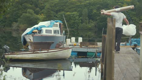 man walking down pier with supplies to renovate old wooden boat into liveaboard