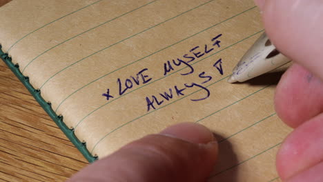 writing self love note on notebook paper, macro close up view