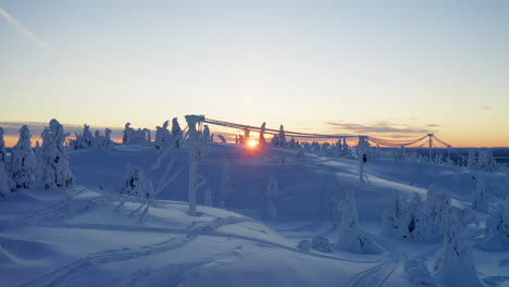 precision aerial view flying between snow covered cables in haunting alien alpine winter woodland landscape at sunrise