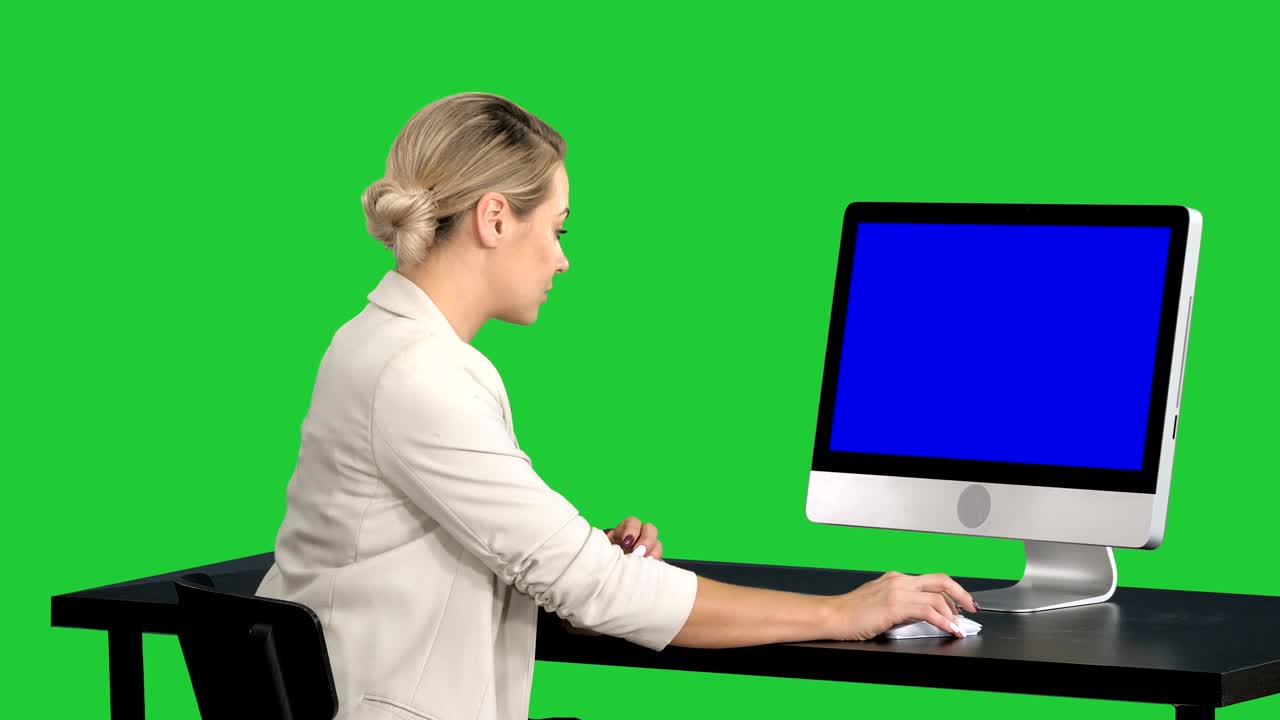 Young pretty lady talking to the camera and showing something on the screen of the computer on a Green Screen, Chroma Key. Blue Screen Mock-up Display