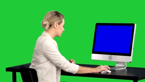 young pretty lady talking to the camera and showing something on the screen of the computer on a green screen, chroma key. blue screen mock-up display