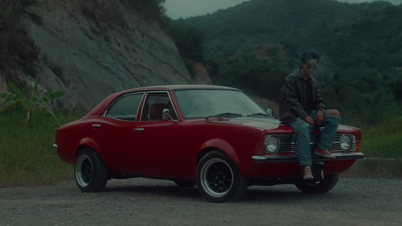 Man Sitting on Classic Red Car in Nature