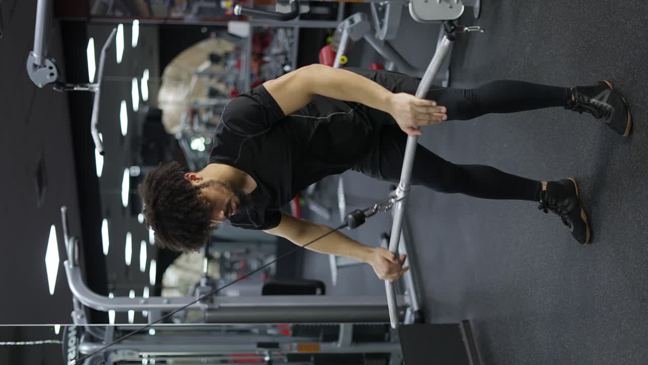 joven haciendo ejercicio de tracción lateral en el gimnasio para los músculos de la espalda