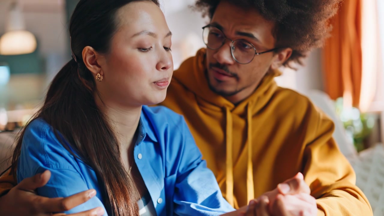 Closeup distressed woman comforted by boyfriend at home. Couple supporting