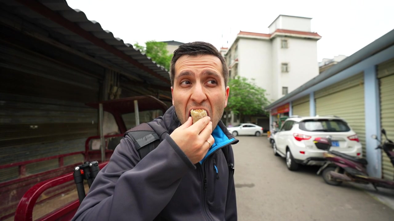 Caucasian man eating asian food outdoors, looking at the camera in a vlog style