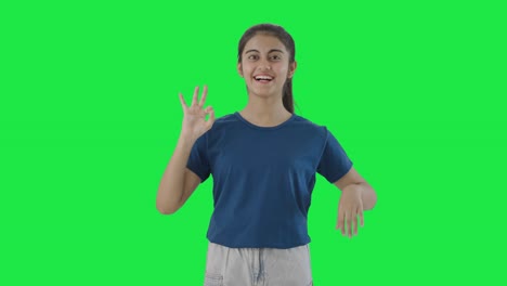una adolescente india feliz mostrando una pantalla verde con un letrero de acuerdo
