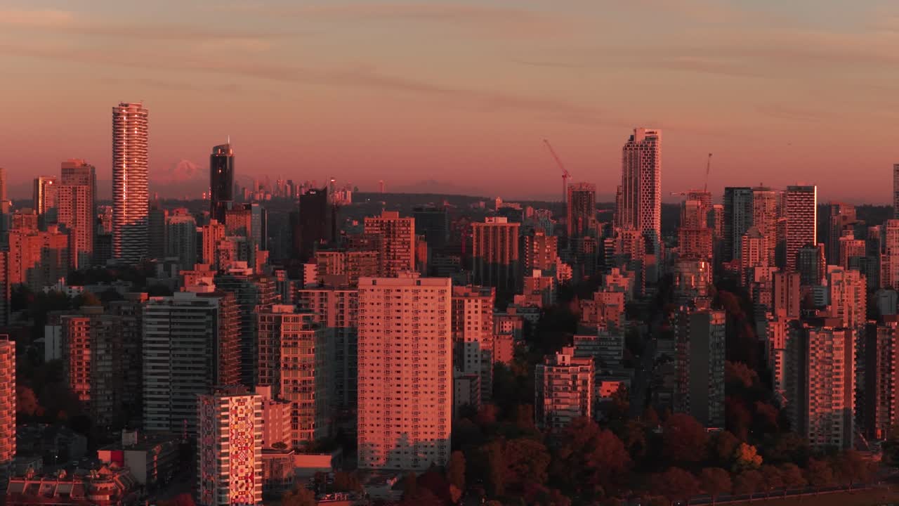 Telephoto wide aerial dolly shot of skyscrapers along English Bay during sunset in downtown Vancouver, British Columbia, Canada. 4K