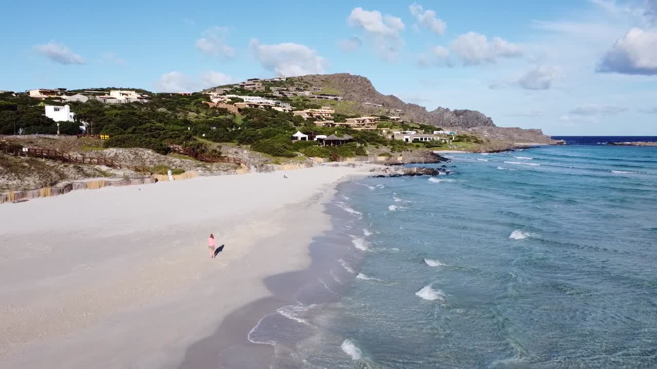 hermosa chica rubia caminando en una increíble playa blanca en cerdeña, clima soleado