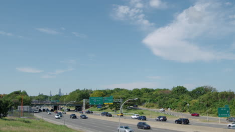 nyc's grand central parkway with moderate traffic on clear day with commercial jet passing low overhead