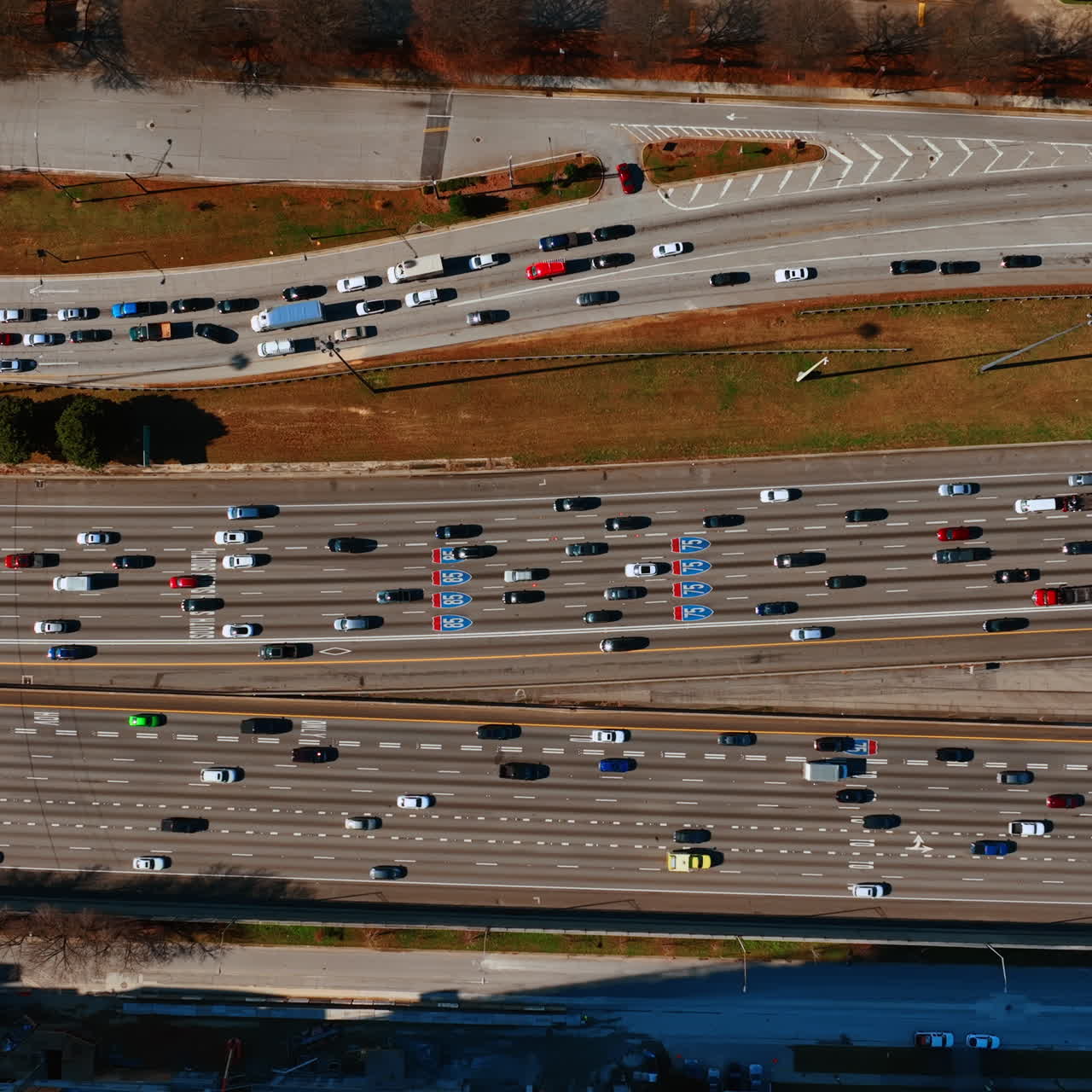 Numerous cars and lorries move to both sides of the road. Top view on the speedway on daytime.