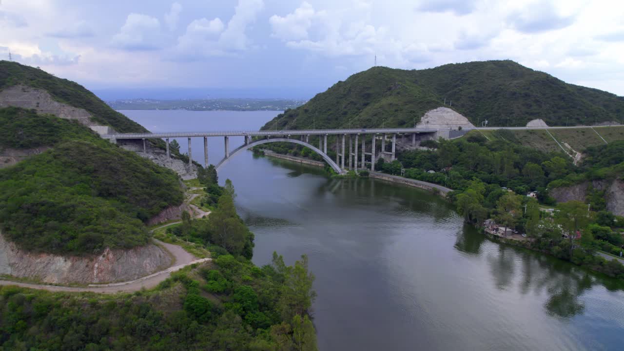 Aerial view of bridge over lake surrounded by green mountains. Córdoba, Argentina