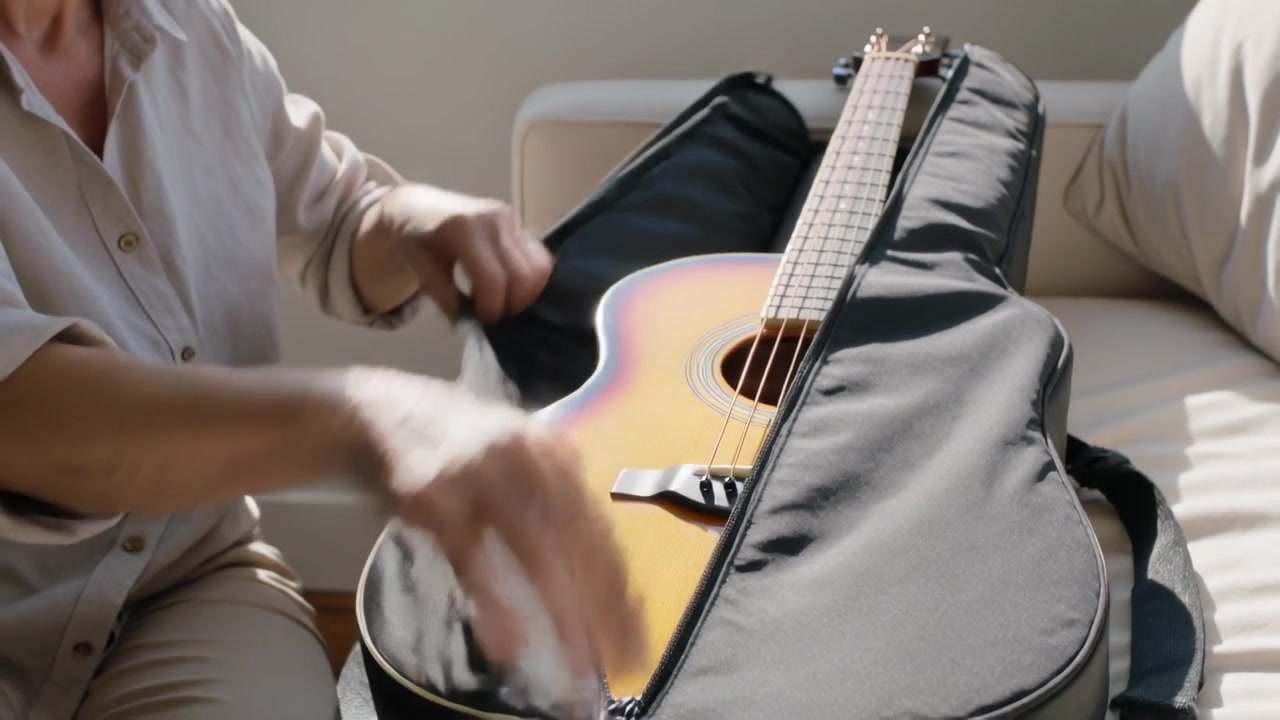 Fermuarı kavrayan, açık renk gömlekli yaşlı kadın pencere kenarındaki kanepede gitar çantasını açıyor, gitarı çıkarıyor