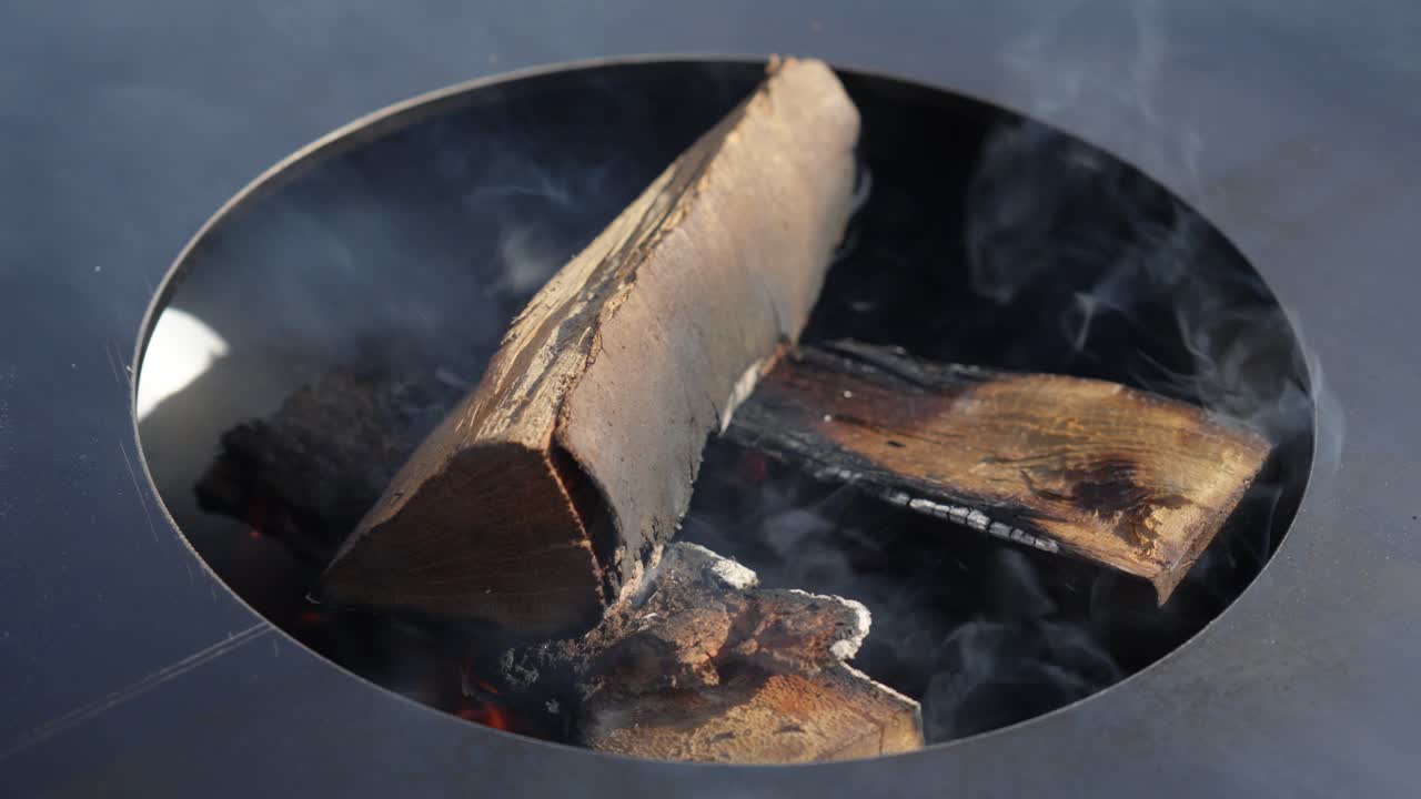 orbiting shot of smoke rising from the burning wooden logs for a bbq