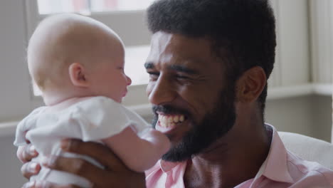 Loving-Father-Playing-With-Smiling-Baby-Daughter-At-Home