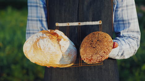 Ein-Bäcker-Hält-Zwei-Laibe-Helles-Und-Dunkles-Brot