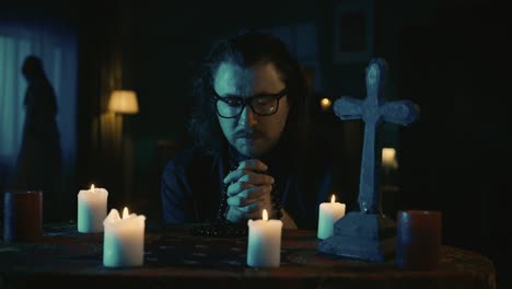 video capturing a table with magical tools on it a priest is sitting at the table with beads in his - video capturing a table with magical tools on it. a priest is sitting at the table with beads in his hands, praying with his eyes closed, when a hand lays on his shoulder. creative content, hallowee