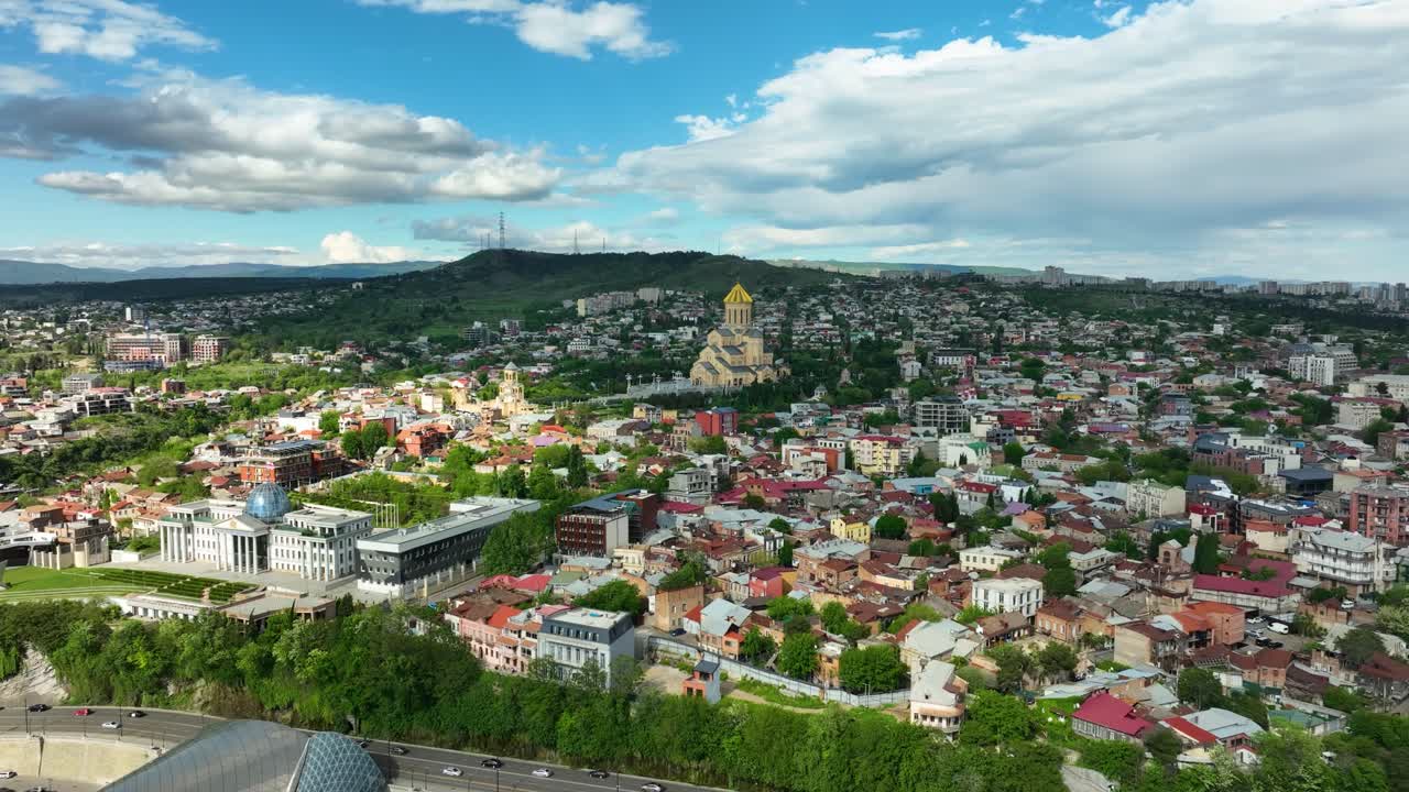 A breathtaking panoramic drone video of Tbilisi’s residential districts and churches spread across rolling hills under a bright blue sky