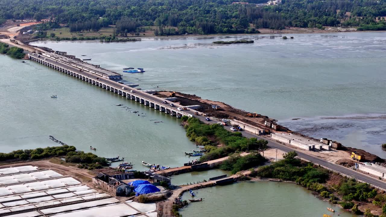 High-angle footage depicts a bridge under development, connecting land across a vast waterway in Chennai, highlighting both active traffic and ongoing construction