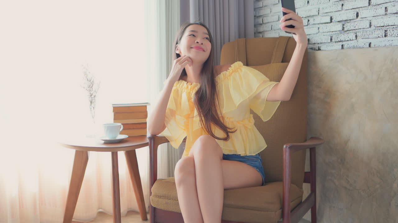 An Asian woman is taking a selfie on a chair