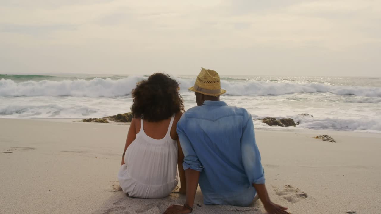 Rear view of African American couple relaxing together on the beach 4k