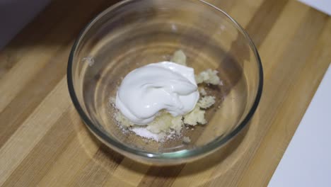 a close-up video showing the process of making garlic sauce by mixing mashed garlic, salt, and creamy ingredients in a bowl. perfect for cooking lovers.