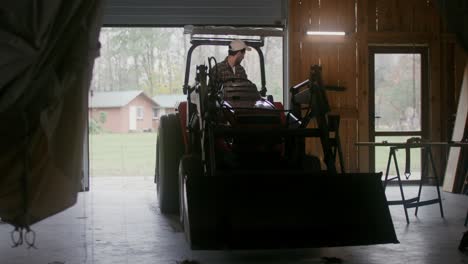 farmer driving tractor in barn