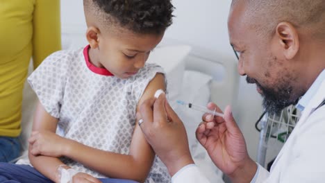 Médico-Varón-Afroamericano-Vacunando-A-Un-Paciente-Infantil-En-El-Hospital