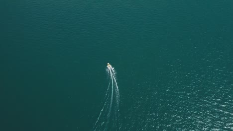Drone-shot-of-sports-boat-on-turquoise-water-of-lake-Garda-in-Italy