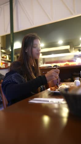 young woman eating in restaurant