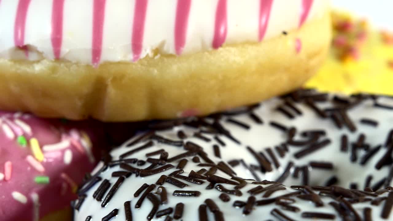 rosquillas giratorias con diferentes rellenos en la mesa. deliciosa rosquilla dulce girando en un plato. rosquilla brillante y colorida macro disparo de primer plano girando sobre un fondo blanco. bucle sin costuras.