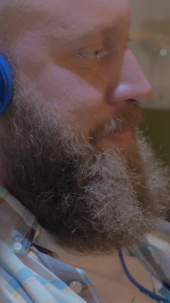 Close up view of two bearded men listening musics using colorful on-ear headset
