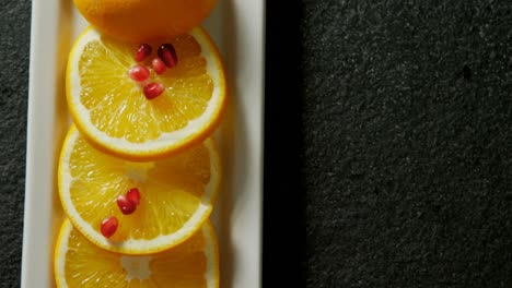 slice of orange with pomegranate seeds in tray on black background 4k 4k