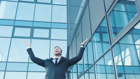 a young smiling office worker he spread his arms wide looks around and rejoices a young smiling office worker he spread his arms wide looks around and rejoices business worker on the background of the newest business center business concept