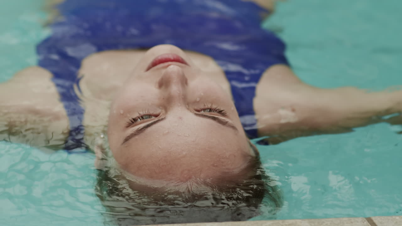 mujer joven flotando en la espalda en la piscina