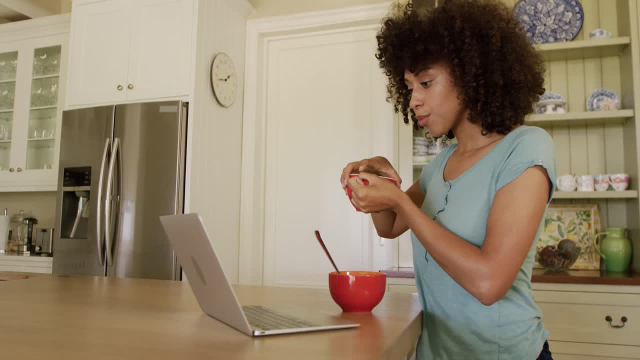 mujer de raza mixta comiendo el desayuno en su cocina