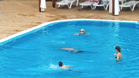 personas sentadas a la orilla de la piscina de un resort durante las vacaciones de verano