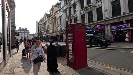 people walking past a red phone booth