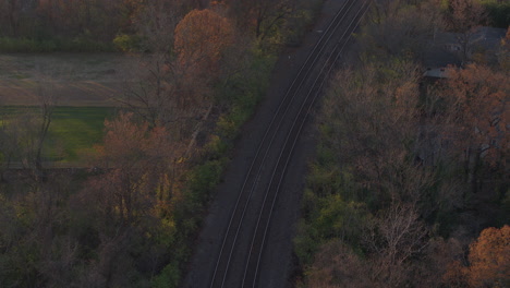 Vista-Aérea-De-Las-Vías-Del-Tren-En-Un-Pequeño-Pueblo-En-Otoño-Con-Inclinación-Hacia-Arriba