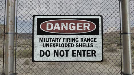 high quality 3d cgi render with a smooth dollying-in shot of a chainlink fence at a high security installation in a desert scene, with a danger military firing range sign