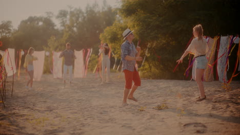 una joven pareja bailando mientras sus amigos se divierten en la playa