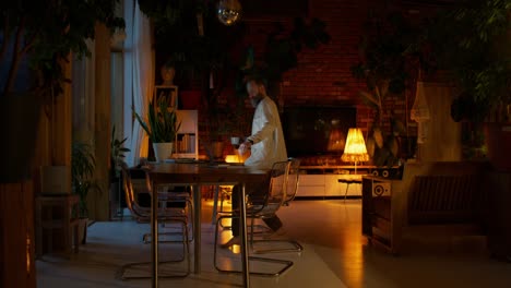 hombre trabajando en una computadora portátil por la noche en una casa acogedora