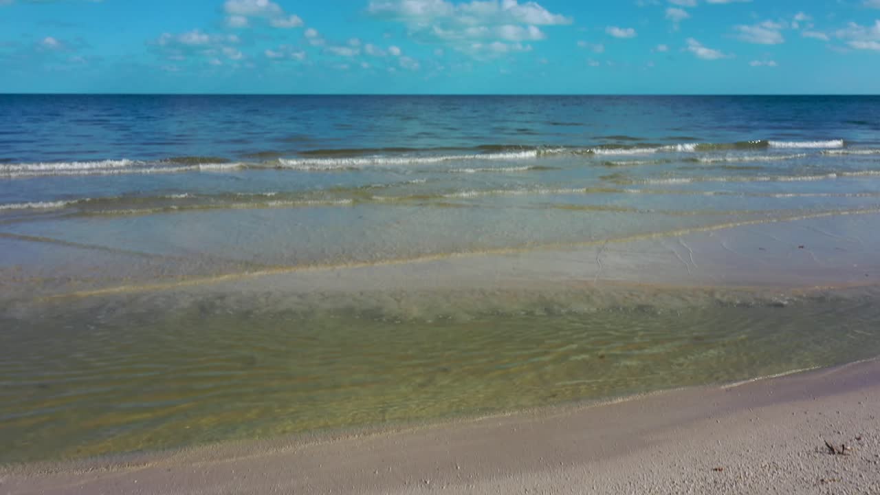 la cámara se inclina hacia arriba desde te amo escrito en la arena de una playa hasta el horizonte que muestra el océano