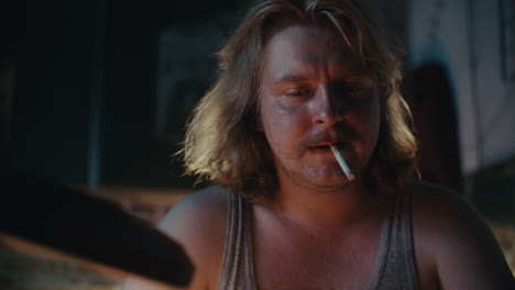 man smoking a cigarette in a dimly lit room