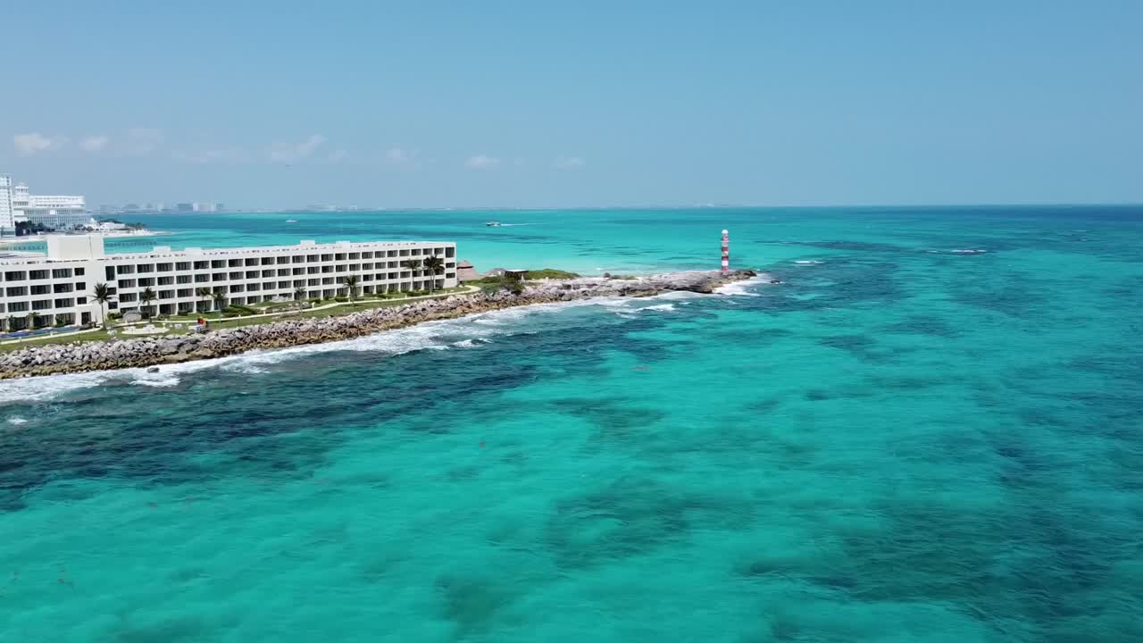 Costa di Cancun con faro e hotel, acque limpide e blu sotto cieli soleggiati, vista aerea