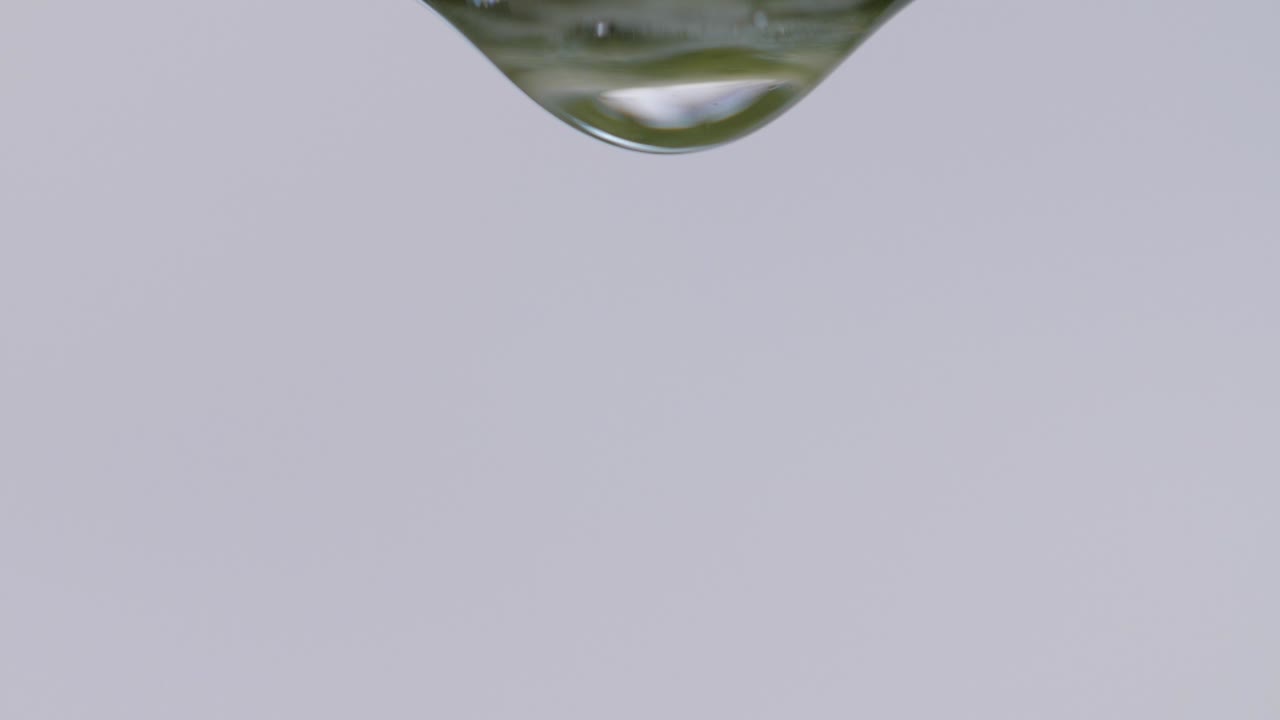 una gota de agua que se origina en una superficie húmeda y cae en una hermosa toma macro en cámara lenta